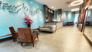 A lobby with a seating area, a reception desk, and a decorative wall. - Win Hotel (Sibu)