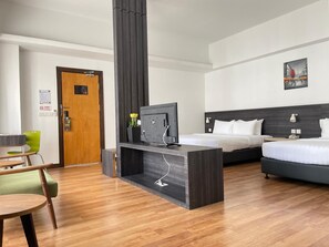 A hotel room with a bed, a desk with a television, a chair, and a door. - Win Hotel (Sibu)