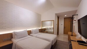 A hotel room with two beds, a TV, a mirror, and a wooden desk. - Ra Inn Kemang (Jakarta)