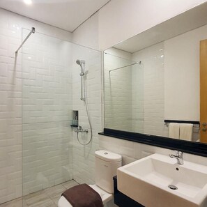 A bathroom with a glass-enclosed shower, a white sink, and a mirror above the sink. - Ra Inn Kemang (Jakarta)