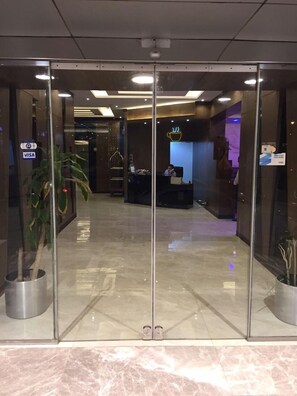 A modern lobby with a reception desk, a coffee symbol sign, and a VISA sign on the door. - Rukon Buotat 15 (Riyadh)