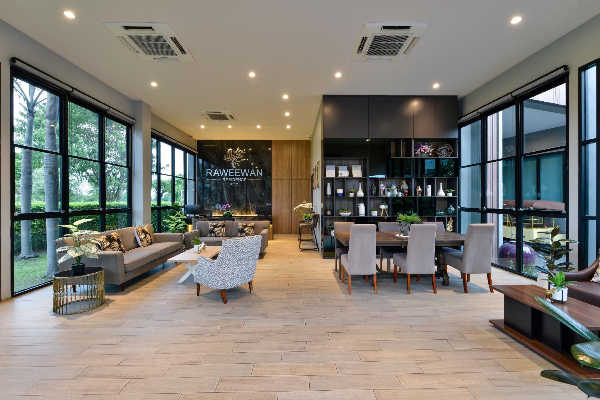 A spacious living area with a sofa, chairs, a dining table, and a bookshelf.
