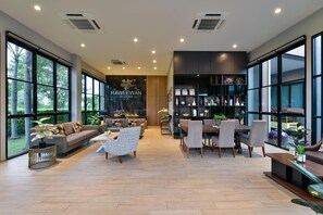 A spacious living area with a sofa, chairs, a dining table, and a bookshelf. - Raweewan Residence (Bangkok)