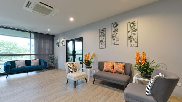 A modern living room with a sofa, chairs, and a coffee table. There are potted plants and artwork on the walls. - Raweewan Residence (Bangkok)