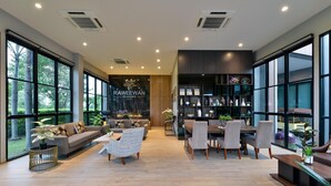 A spacious living area with a sofa, chairs, a dining table, and a bookshelf. - Raweewan Residence (Bangkok)