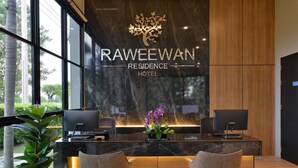 A reception desk with a modern design, featuring a logo and the name "RAWEWAN RESIDENCE HOTEL". - Raweewan Residence (Bangkok)