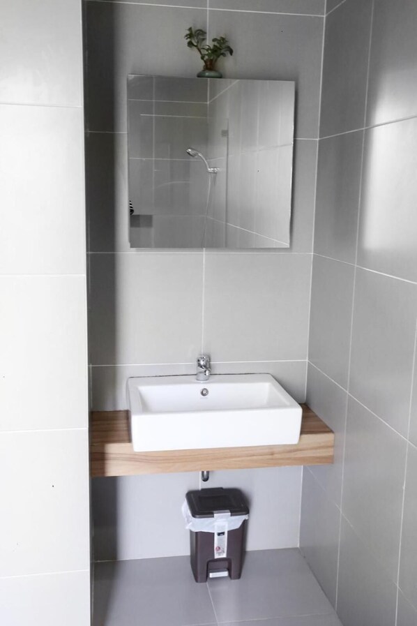 A bathroom with a white sink, a mirror above it, and a small trash bin below. - M Pavilion Karawaci (Curug)