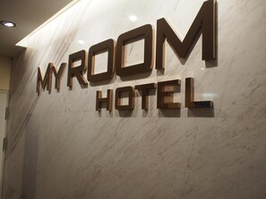 Un muro in marmo con la scritta "MYROOM HOTEL" in grandi caratteri in evidenza.