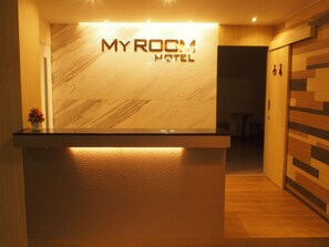 Una reception con una parete in marmo e un cartello con la scritta 'MYROOM HOTEL'.
