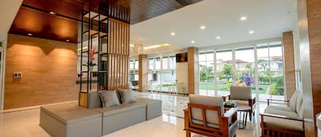 Uma sala de estar espaçosa com design moderno, apresentando um sofá seccional, móveis de madeira e grandes janelas com vista para o exterior.