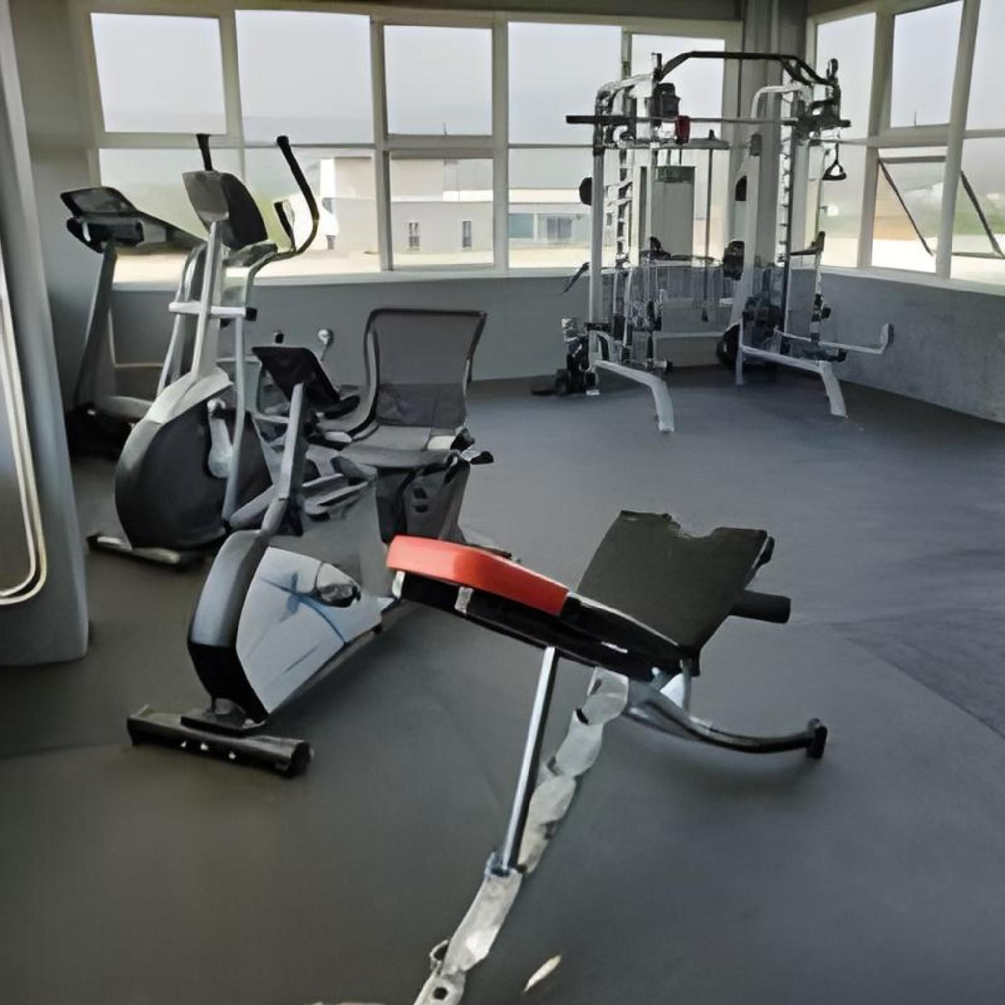 A gym with various exercise machines, large windows, and a view of the outside.