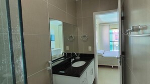 A bathroom with a black countertop sink, a mirror, and a toilet with a grab bar. - 15 suites in the center of Porto de Galinhas. Oasis on the most beautiful beach in Pernambuco. (Ipojuca)