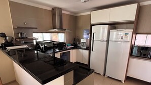 A modern kitchen with a central island, white cabinets, and stainless steel appliances. - 15 suites in the center of Porto de Galinhas. Oasis on the most beautiful beach in Pernambuco. (Ipojuca)