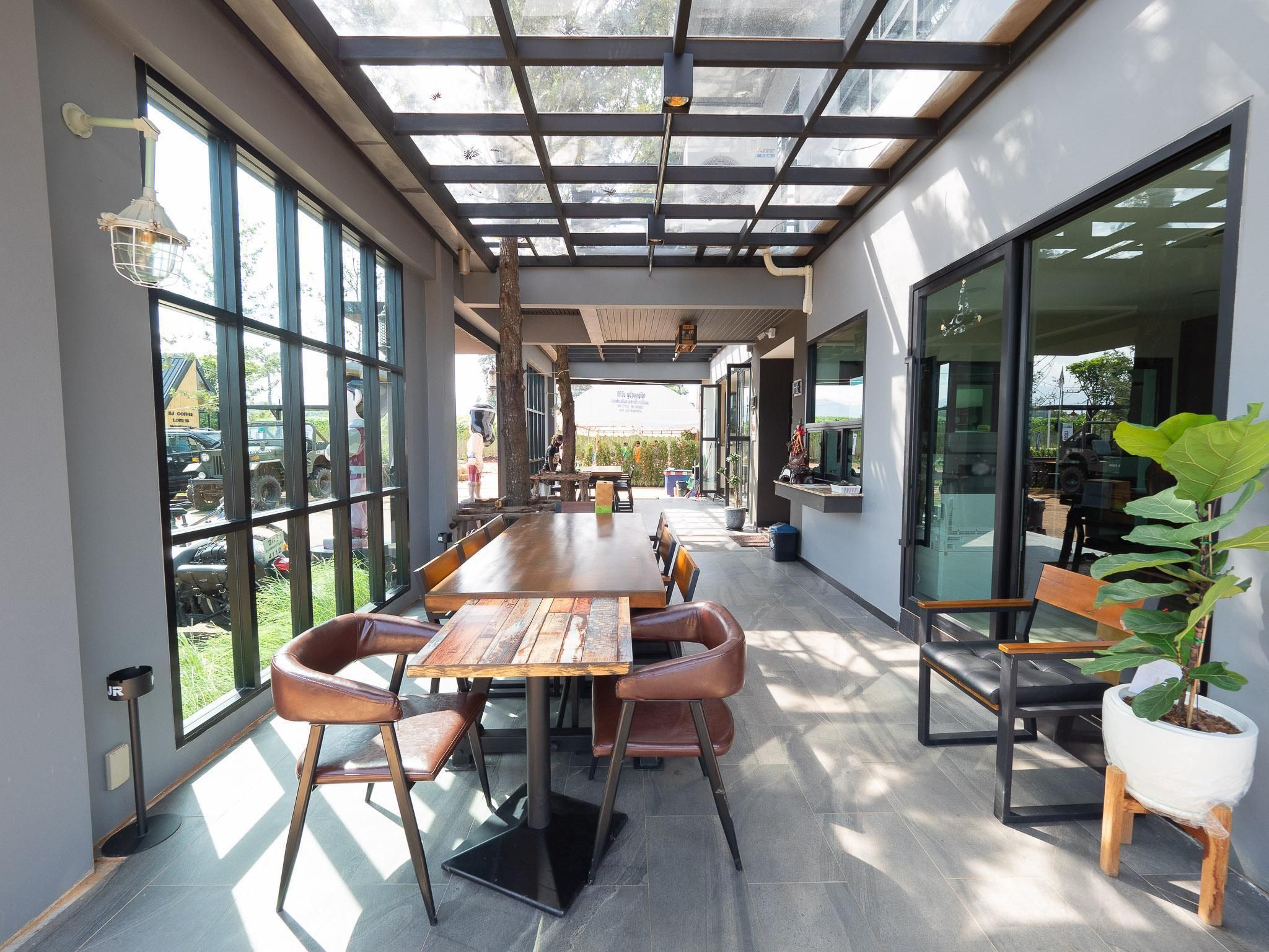 An indoor dining area with a long wooden table, leather chairs, and large windows.