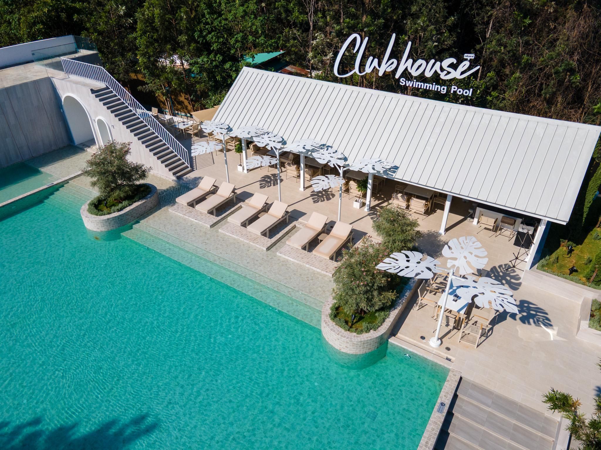 An aerial view of a Clubhouse Swimming Pool with a covered seating area, lounge chairs, and a staircase leading to an upper level.