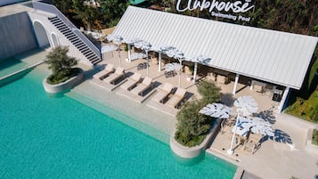 An aerial view of a Clubhouse Swimming Pool with a covered seating area, lounge chairs, and a staircase leading to an upper level.