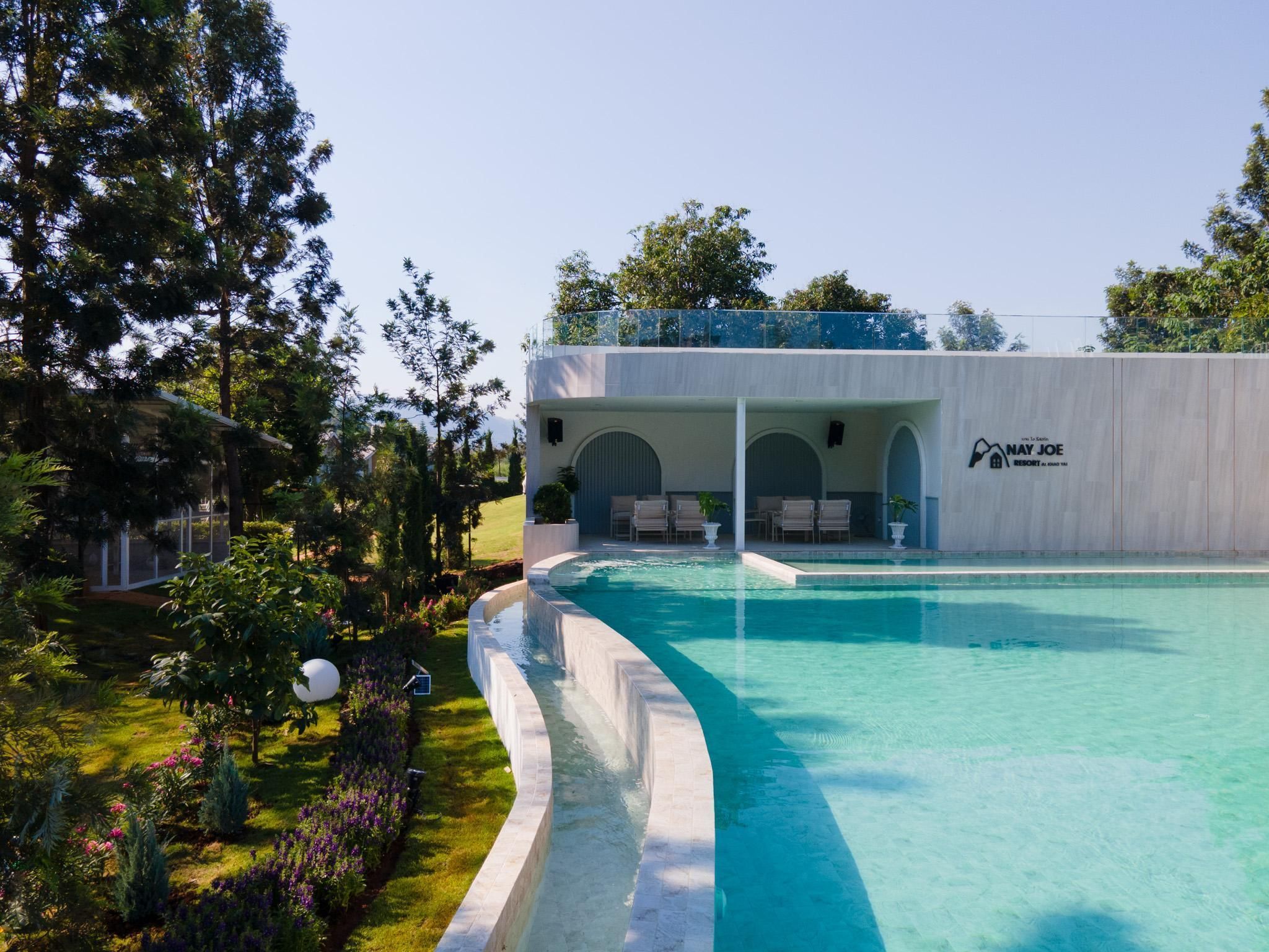 A resort with a swimming pool, outdoor seating, and a covered area with a logo.