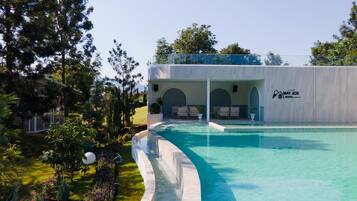 A resort with a swimming pool, outdoor seating, and a covered area with a logo.