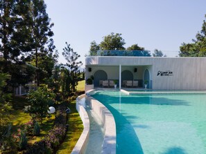 A resort with a swimming pool, outdoor seating, and a covered area with a logo. - Nay Joe Resort (Pak Chong)