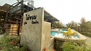 A concrete structure with a pool and inflatable rings, surrounded by greenery and a building with a metal staircase. - Maai Horm Boutique Resort (Muak Lek)