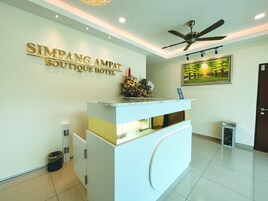 Un mostrador de recepción con un letrero que dice "SIMPANG AMPAT BOUTIQUE HOTEL" en la parte superior.