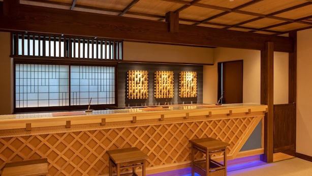 A traditional Japanese-style bar with wooden lattice partitions, a low counter, and two stools. - Onyado Shikishimakan (Kotohira)