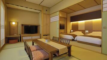 Una habitación tradicional japonesa con suelo de tatami, una mesa baja, dos camas con cabeceras, un televisor y una puerta corredera.