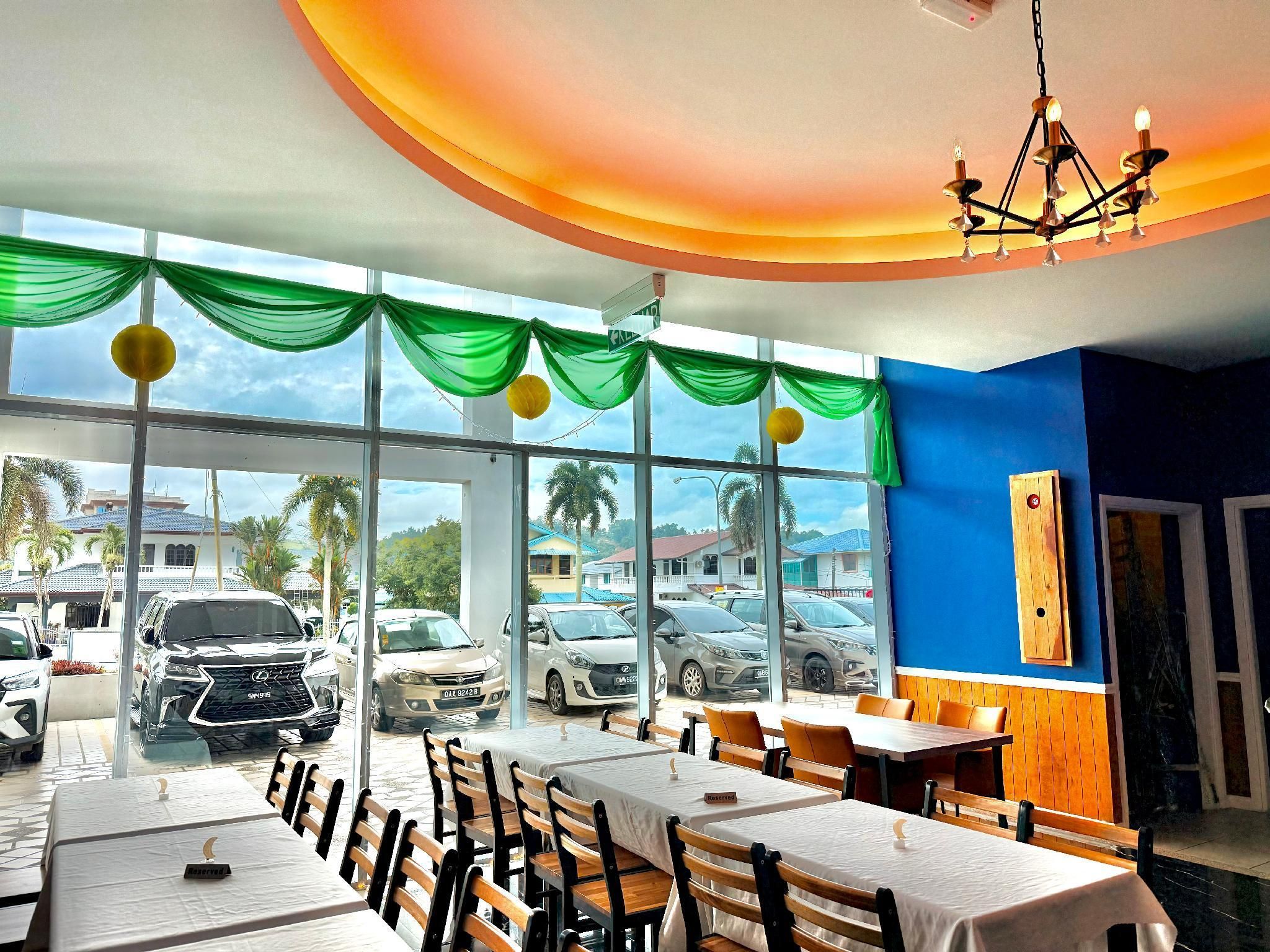 A restaurant with large windows, green drapes, and a chandelier.