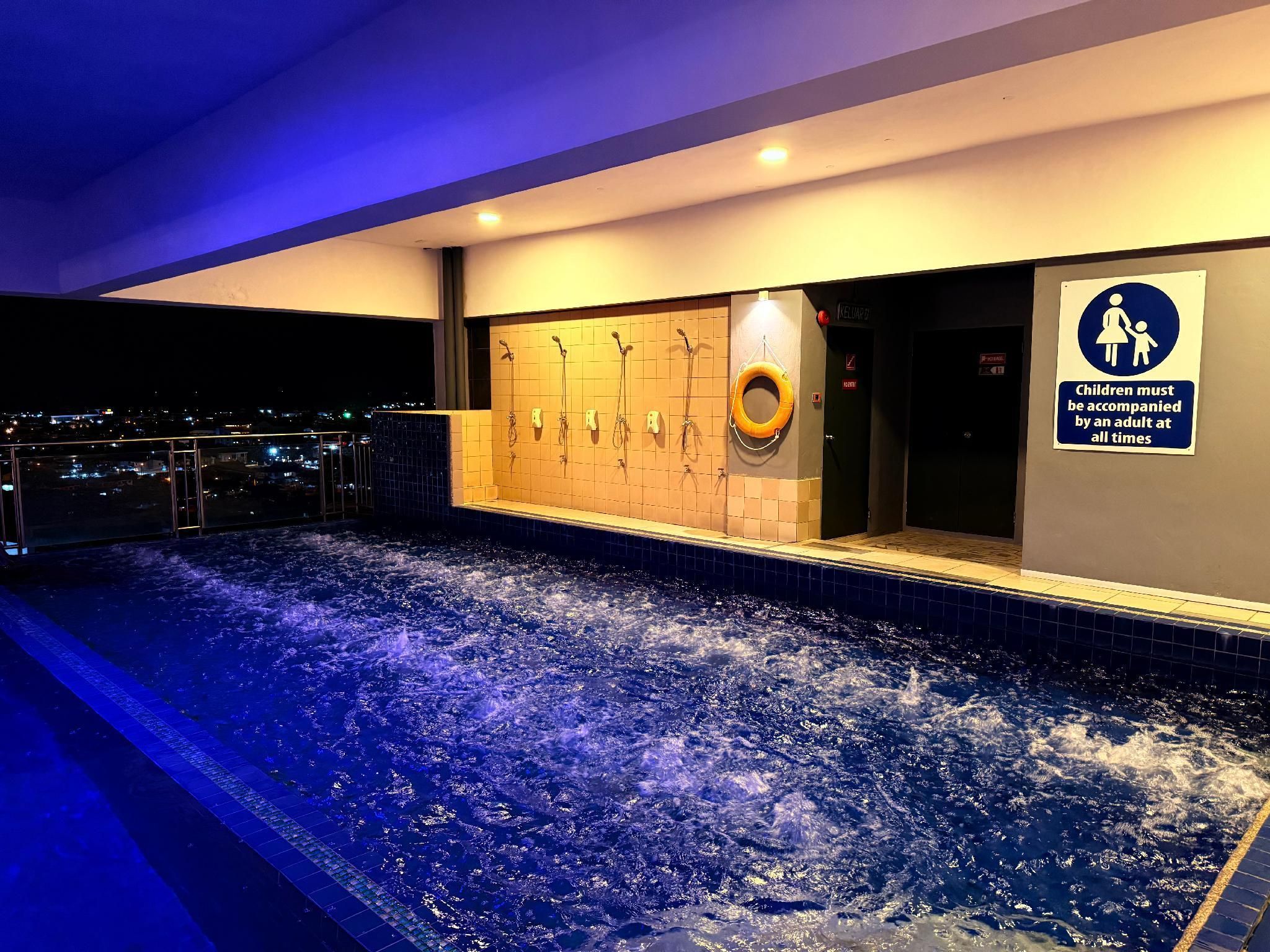 A heated indoor pool with a cityscape view, a changing room with a lifebuoy, and a sign indicating children must be accompanied by an adult.