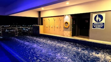 A heated indoor pool with a cityscape view, a changing room with a lifebuoy, and a sign indicating children must be accompanied by an adult.
