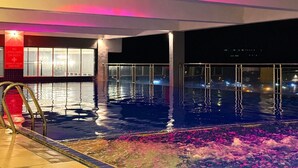 An indoor swimming pool with a view of the city at night. - Stirling Suites Hotel & Serviced Apartment (Miri)