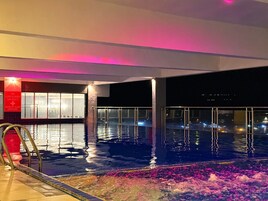 Una piscina interior con vistas a la ciudad de noche.