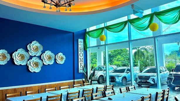 A restaurant with blue walls, white flower decorations, and a 'Welcome to our HOME' sign. Tables are arranged for dining. - Stirling Suites Hotel & Serviced Apartment (Miri)