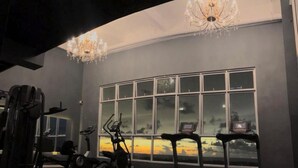 A gym with exercise equipment, a large window with a sunset view, and chandeliers. - Stirling Suites Hotel & Serviced Apartment (Miri)