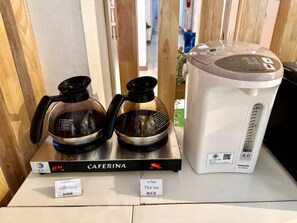 En kaffemaskine og to glas kander på en bordplade med skilte for 'caffeina' og 'thai tea'.