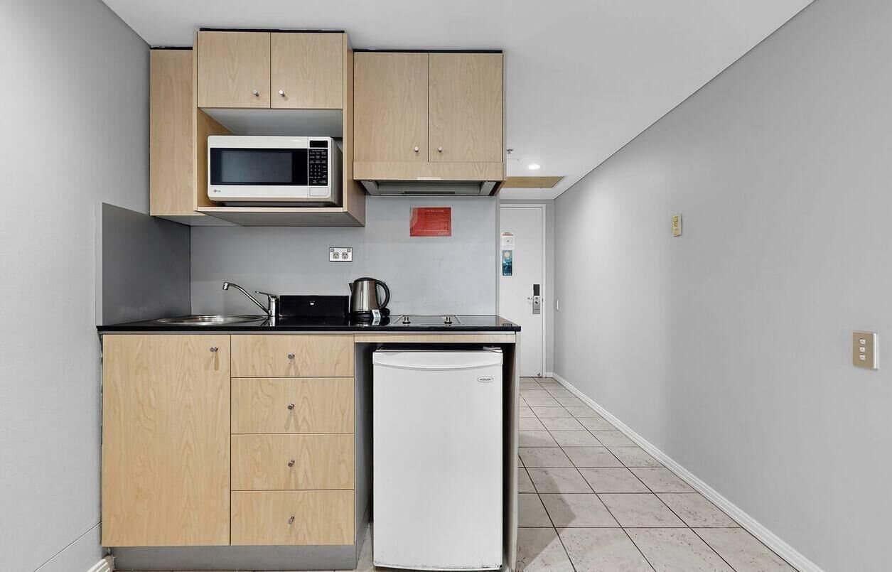 A compact kitchen with a microwave, kettle, and refrigerator.