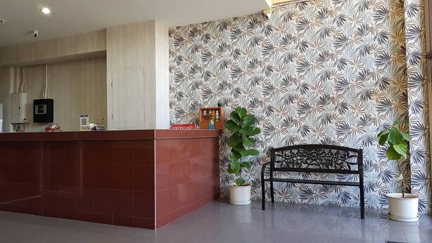 A reception area with a red reception desk, a bench, and two potted plants. - T Bird Grand Hotel Trang (Trang)