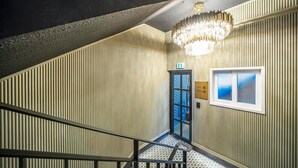 A staircase with a checkered floor leading to a lobby area with a chandelier, a door labeled "Lobby Parking," and a window with a view. - Urbannord (Seoul)