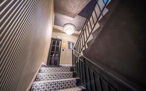 A staircase with patterned steps, a chandelier, and a door with a sign. - Urbannord (Seoul)