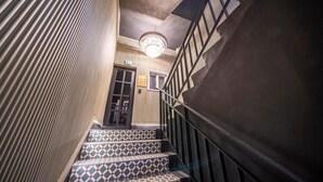 A staircase with patterned steps, a chandelier, and a door with a sign. - Urbannord (Seoul)