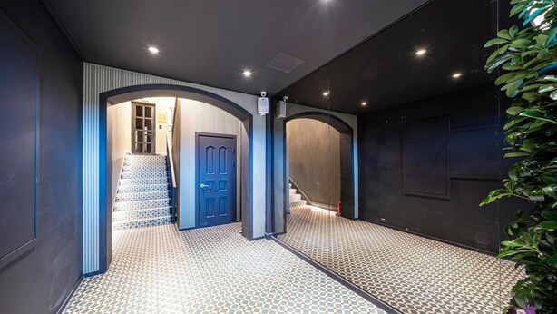 A hallway with patterned flooring, a blue door, and a staircase leading to an upper level. - Urbannord (Seoul)