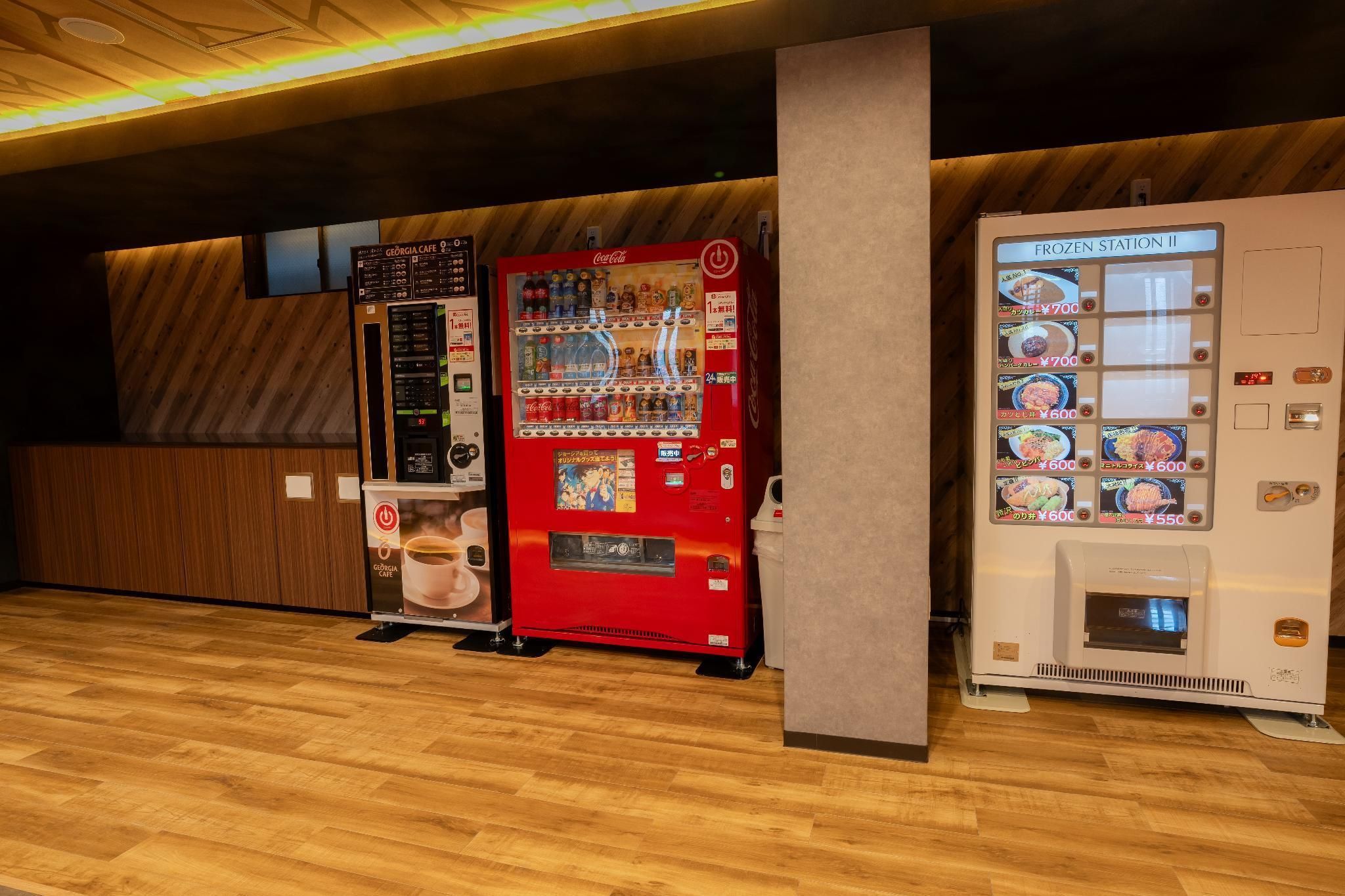 Una hilera de máquinas expendedoras con diversas opciones de bebidas y una máquina de Coca-Cola.