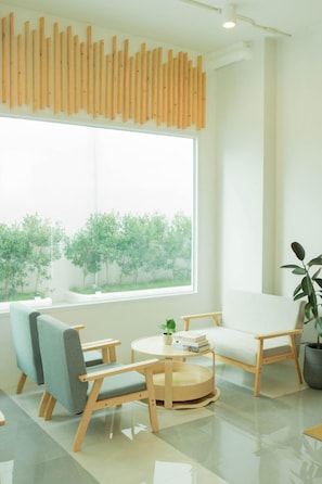 A modern room with a large window, a round wooden table, two chairs, and a potted plant. - S1 Trang Hotel (Trang)