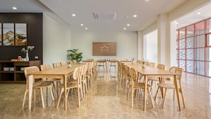 A conference room with a long table and chairs, a plant, and a framed picture on the wall. - Kio Hotel Korat (Nakhon Ratchasima)