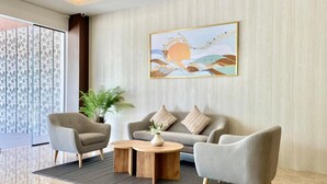 A modern living room with a sofa, two armchairs, a coffee table, and a large abstract painting on the wall. - Kio Hotel Korat (Nakhon Ratchasima)