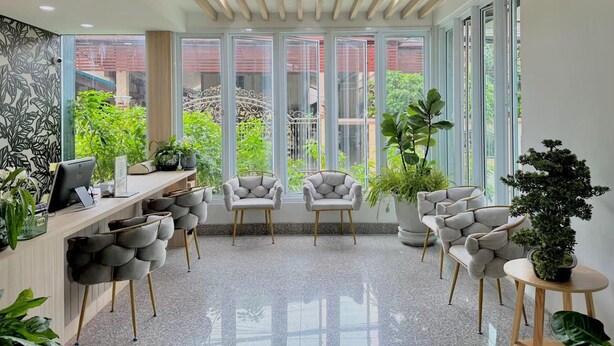 A modern office space with a long desk, multiple chairs, and large windows offering a view of greenery.