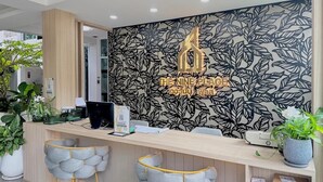 A reception desk with a leaf-patterned wall, a sign reading "The Nine Place," and two cushioned chairs.