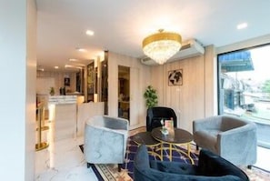 A modern living room with a chandelier, two armchairs, a round coffee table, and a view of the city. - Metro Ratchada 36 (Bangkok)