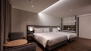 A modern hotel room with a large bed, a desk, a chair, and a small table. - Ramada Suites Geoje (Pyeongtaek)