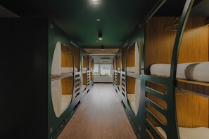 A train carriage with bunk beds, a central aisle, and a window at the end. - Signel Poshtel (Kota Kinabalu)